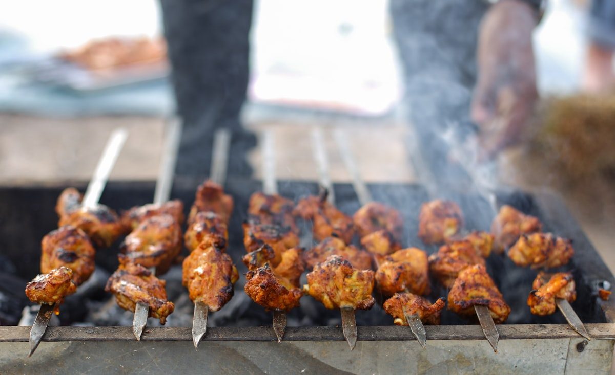 Chicken tikka and tandoori skewers grilling over charcoal — tandoori specialties at Leduc Meat & Grill